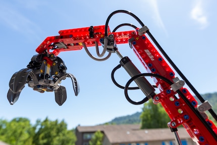 The articulated arm of the excavator with its claw open.