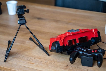 Si controlla il Virtual Boy (destra, al centro) con un controller (destra, in basso). Poiché non è possibile fissarlo alla testa, lo si monta su un treppiede (a sinistra).