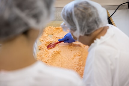 Sandra e Ursula spargono il sale al peperoncino in modo uniforme sul vassoio per farlo asciugare bene.