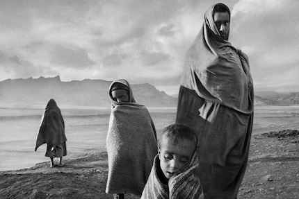 Avvolti in coperte, i rifugiati aspettano fuori da un campo a Korem, in Etiopia, nel 1984.