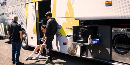 La quiete prima della tempesta alla partenza al bus del team, con la macchina del caffè e la lavatrice personali. In caso di necessità, dei pannelli solari sul tetto forniscono all’autobus parecchie ore di corrente anche a motore spento.