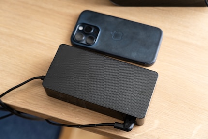 Gli alimentatori esterni consentono di avere dispositivi più leggeri. Sul tavolo, però, bisogna trovare posto per questo. A fianco un iPhone 15 Pro per confronto.
