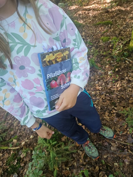 Mia figlia con il manuale dei funghi che ci permette di fare una prima categorizzazione sul posto.
